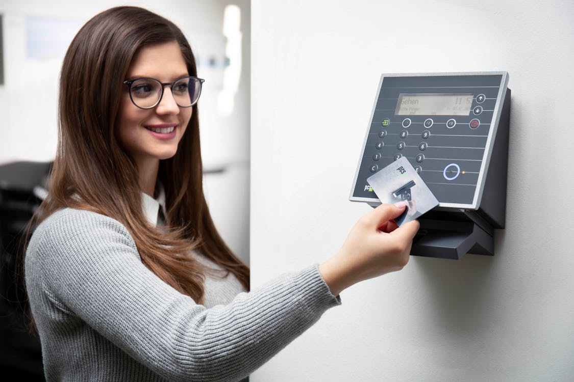 Woman holding an access card against a wall-mounted reader for secure entry