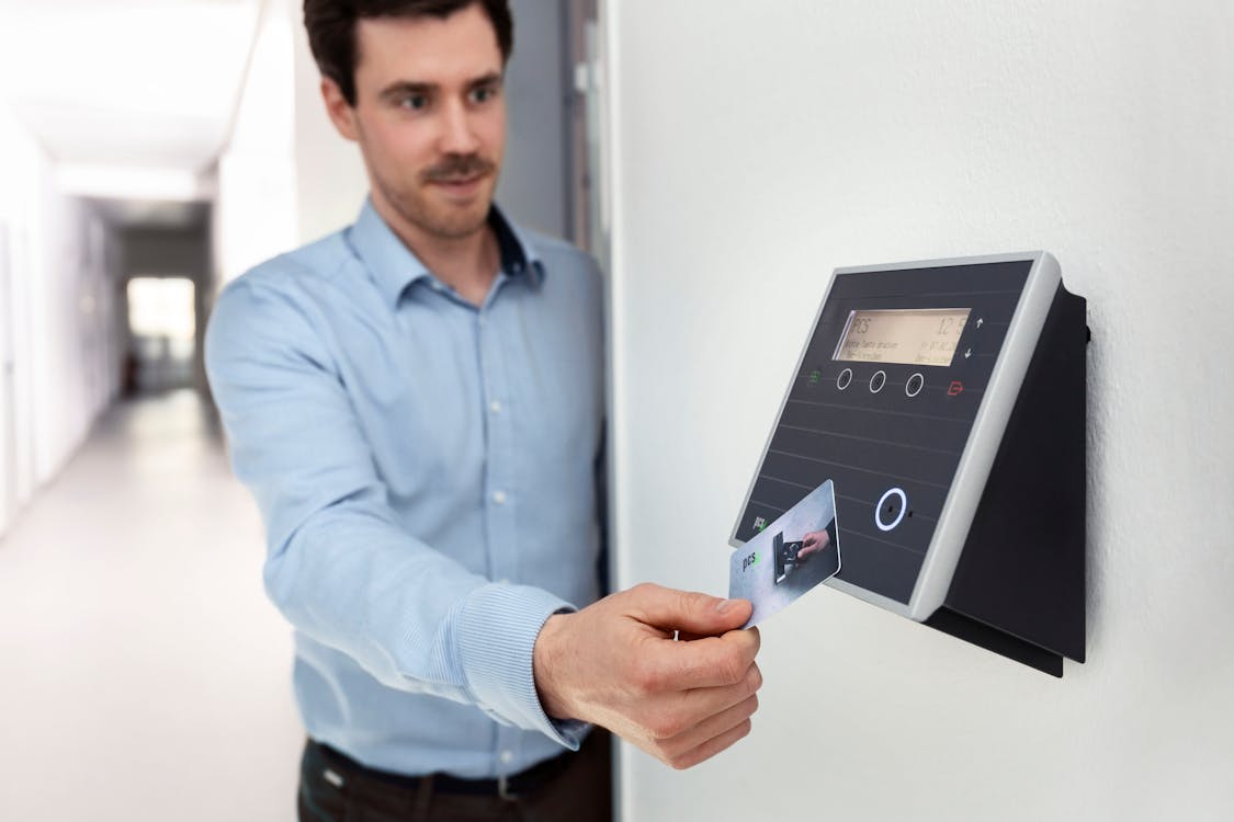 Man authenticating entry by tapping an access card on an electronic door access reader