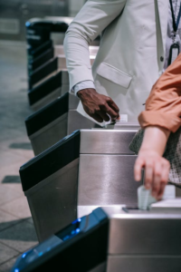 A person tapping a card on a turnstile reader to enter a controlled access lane.